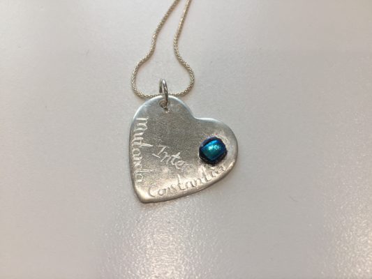 Silver heart pendant with dichroic blue glass detail. Inscribed wiht Inter Mutanda Constantia